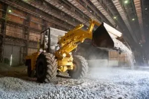 Yellow front-end loader dumping gravel at industrial worksite.